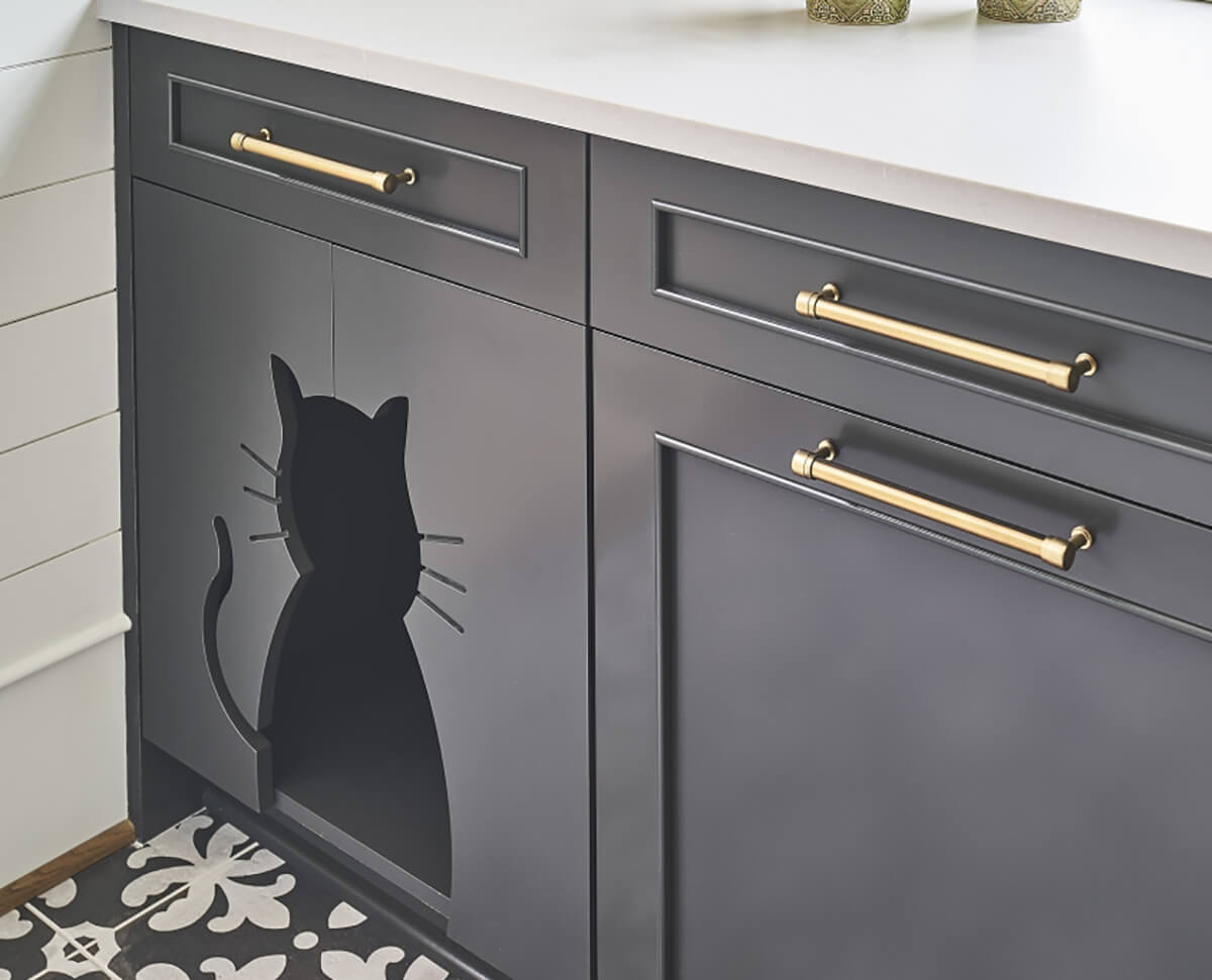 Custom cabinets from Dura Supreme Cabinetry that are hand-crafted and made in America. This gray painted cabinet includes a cat cut out for the cat of the home to access it's hidden food dish.